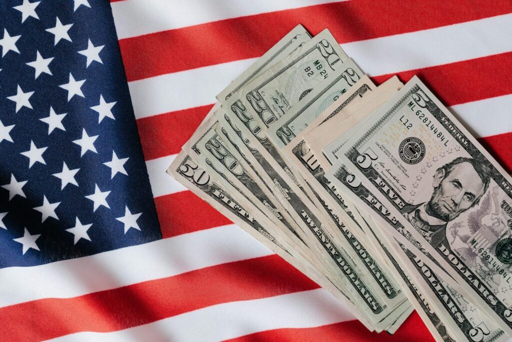 Dollar bills resting on an American flag representing the new $100,000 H-1B fee