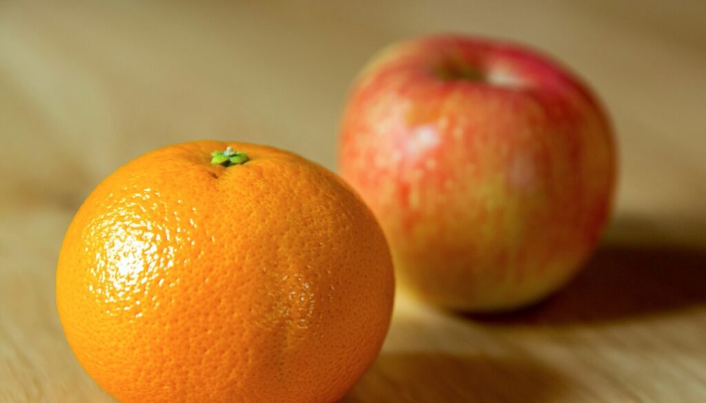 An orange and an apple on a table representing freelance vs. contract